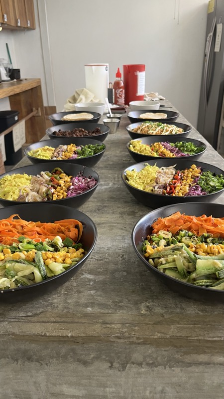 Una mesada larga con bowls de ensalada servidos para todo el grupo.