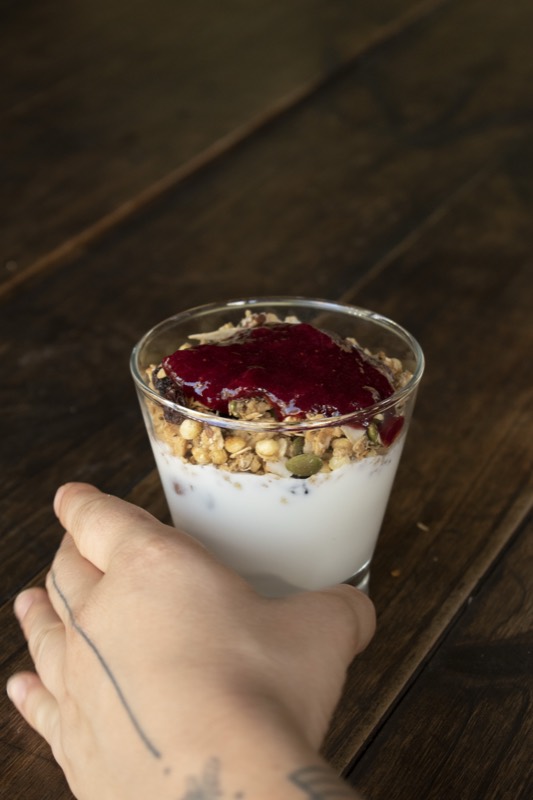 Vaso de yogur con granola y frutos rojos.