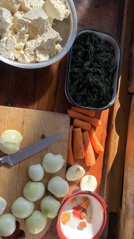 Verduras recién cortadas sobre una tabla de madera: cebollas, zanahorias y espinaca.